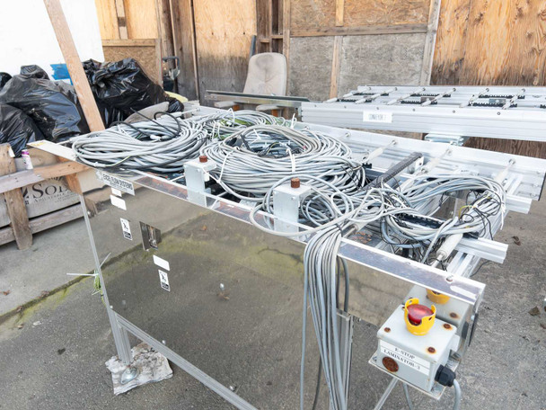 Excel Flow SC23460 conveyor section with bundled gray control cables and yellow/black emergency stop box visible