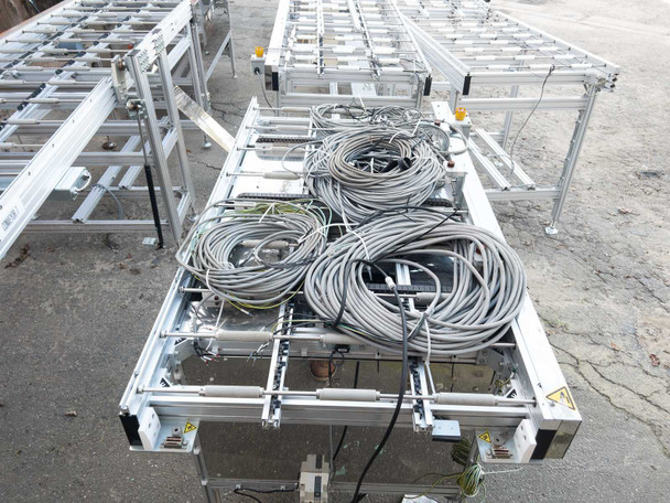 Excel Flow SC23460 conveyor section seen from above with large coils of bundled gray cables resting on roller bed