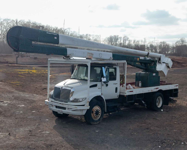 2012 International 4400 Durastar bucket truck with Hi-Ranger 65ft boom stowed – driver side three-quarter front view on dirt lot
