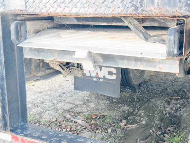 Rear underbody of International 4300 DuraStar showing hydraulic liftgate with RWC Group mudflap; surface rust visible on liftgate frame and undercarriage