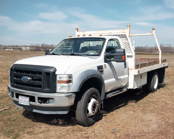 2009 Ford F450 XL Super Duty flatbed truck – front three-quarter view showing Scelzi flatbed and headache rack