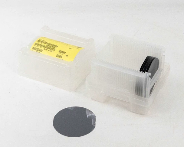 Siltronic AG 100mm FZ polished silicon wafers — two plastic wafer cassettes with one wafer removed and placed in front, showing dark mirror-like polished surface