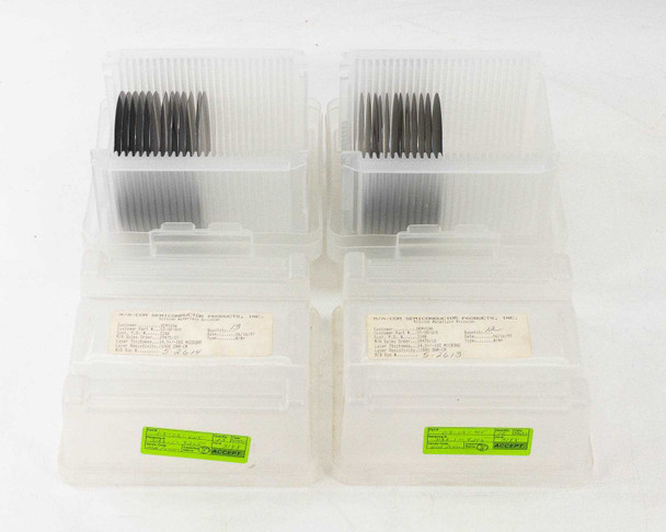 MACOM 100mm polished silicon wafers — four wafer carrier boxes with paper spec labels visible on lids, green barcoded inventory labels on sides
