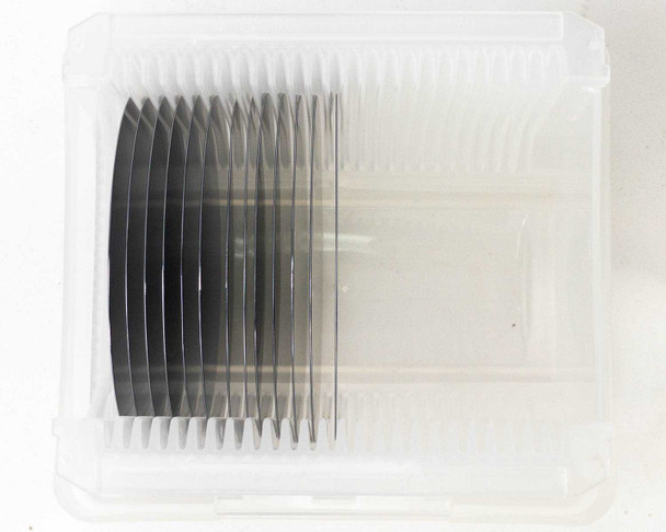 MACOM 100mm polished silicon wafers top-down view inside open carrier — wafers standing vertically in slotted holder showing polished surfaces
