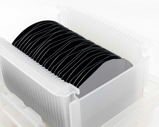SEH America 100mm polished silicon wafers standing vertically in clear plastic wafer carrier — side profile view showing full wafer stack