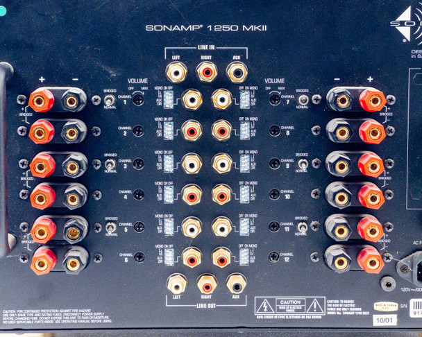 Sonance SONAMP 1250 MKII rear panel close-up — Line In RCA jacks (Left, Right, Aux), per-channel volume knobs, and Mono On/Off and bridged toggle switches for channels 1-6