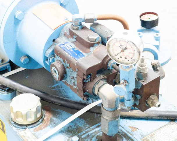 Top-mounted pump and valve block assembly with pressure gauge, copper tubing, and fittings — moderate surface rust on pump body