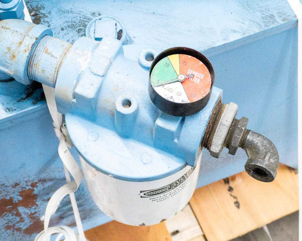 Return line hydraulic filter assembly with color-coded service indicator gauge — filter canister and elbow fitting visible