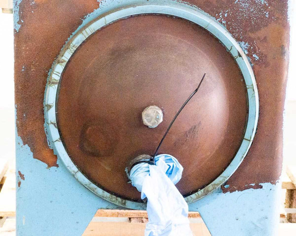 Large oval reservoir cleanout port — front face showing significant surface rust on steel cover and surrounding tank wall