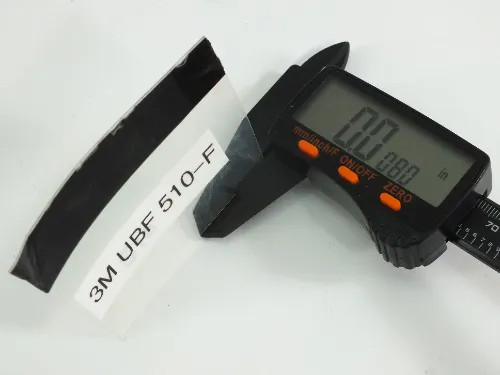 3M UBF 510-F labeled film sample strip held in digital caliper measuring approximately 0.88 inches wide showing film thickness and flexibility