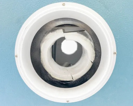 Opposite tube opening on blue front panel of Lindberg 54434 showing aluminum collar and cracked refractory ceramic end cap with visible wear