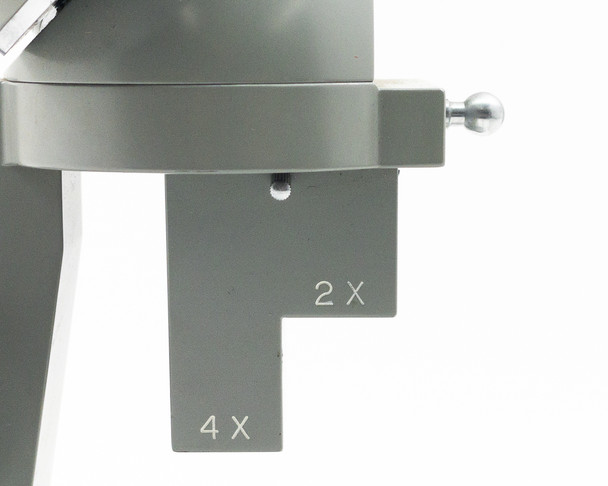 Close-up of dual objective turret showing engraved 2X and 4X markings on the two objective positions