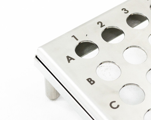 Close-up of CMI stainless steel test tube rack top surface — detail of drilled holes with row A and columns 1–3 visible with etched labels