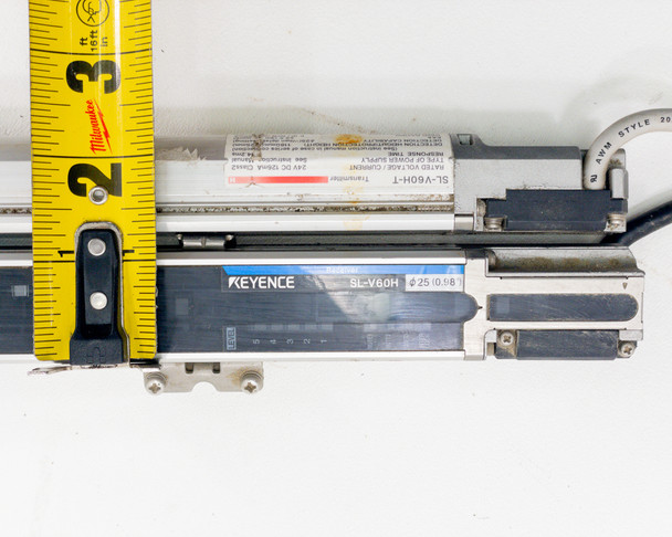 Side-by-side view of Keyence SL-V60H-T transmitter and SL-V60H-R receiver with tape measure confirming approximately 2-inch end-cap width and connector detail