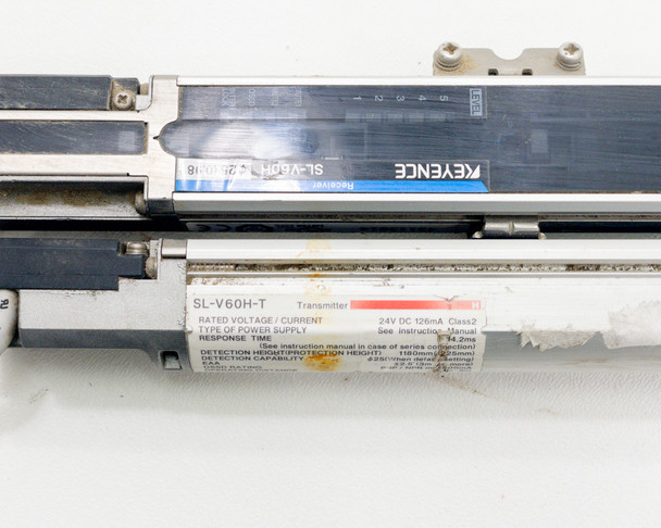 Keyence SL-V60H-T transmitter and SL-V60H-R receiver lying parallel showing full-length bar housings, blue Keyence branding labels, and specification sticker detail