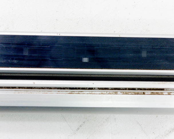 Close-up of Keyence SL-V60H receiver bar face showing lens array surface with surface marks and minor soiling on the optical window