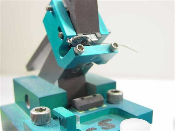 Pneumatic actuator stage close-up – teal anodized body with pivot arm, contact probe tip, and adjustment hardware