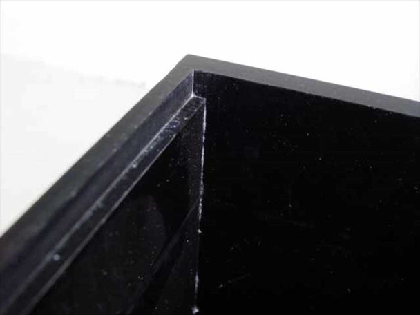Close-up corner detail of black acrylic dry box showing panel joint construction and minor surface scratching