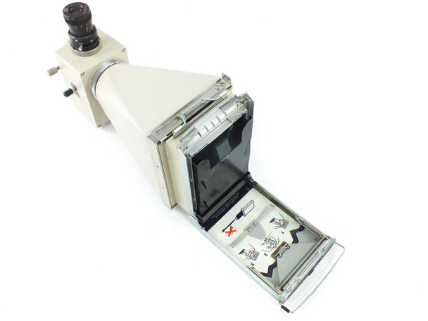 Olympus PM-10AD photomicrography camera with Polaroid back open showing internal film loading mechanism and instruction diagram