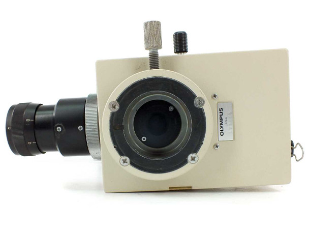 Olympus PM-10AD camera head close-up — side view showing Olympus Japan label, large circular lens port, and focus adjustment knobs