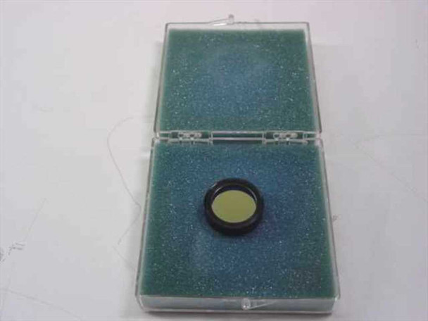 Ealing 35-3441 bandpass optical filter in open foam-lined case — angled view showing yellow-green filter glass in black ring mount