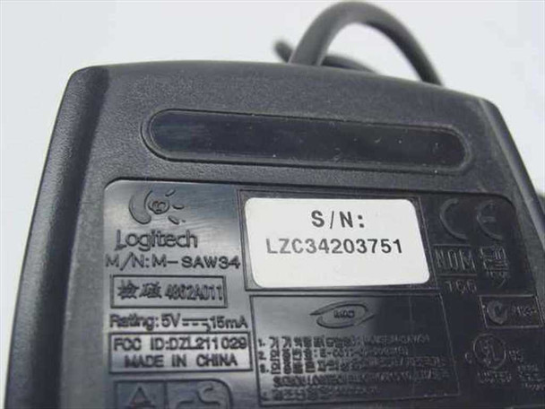 Dell Logitech M-SAW34 mouse — bottom label showing model M-SAW34, Logitech branding, FCC ID DZL211029, 5V 15mA rating, Made in China, and serial number sticker