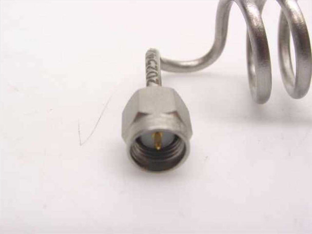 Close-up front face view of SMA-male connector on stainless steel coiled coaxial cable showing gold center pin detail