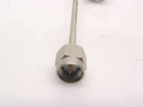 Close-up of SMA male (SMA-M) connector end on stainless steel coiled coaxial cable assembly, showing gold center pin and hex body