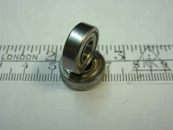 Steel miniature double-shielded ball bearing 1/4 inch bore shown at an angle alongside a ruler — side profile view showing 5mm width