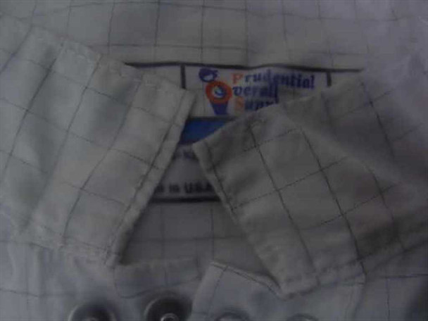 Prudential Overall Supply cleanroom frock interior label showing brand name and knit cuff detail with snap buttons