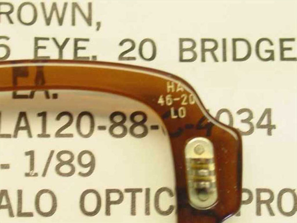 Close-up of Halo Optical military spectacle frame corner showing stamped markings HA 46-20 LO and hinge hardware, with partial DLA label visible