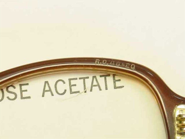 Close-up of Rochester Optical eyeglass frame bridge showing stamped size markings R.O. 46-20 on the bridge, with cellulose acetate label visible beneath