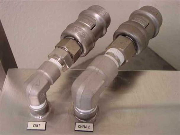 Two labeled stainless steel quick-connect couplings on elbow fittings – marked VENT and CHEM 2 – on cart shelf surface