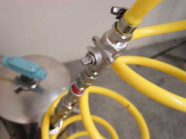 Close-up of yellow hose manifold junction showing quick-disconnect fittings, valves, and hose routing between tanks