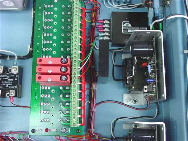 Interior detail showing green controller terminal board with Opto 22 style I/O connections, solid state relays, and regulated power supply mounted in right side of enclosure