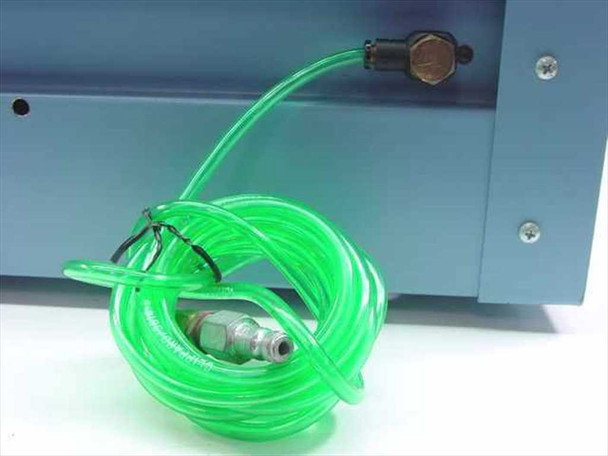 Green pneumatic tubing coiled beside blue enclosure with brass quick-connect fitting and inline valve, used for air/gas flow connections