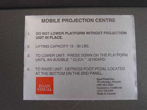 Egan Visual S2PM Mobile Projection Centre instruction label showing foot pedal raise/lower instructions and 15–30 lb lifting capacity – cabinet side panel