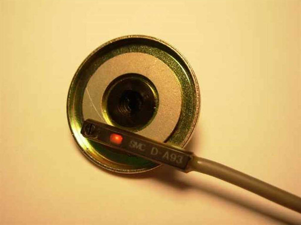 SMC D-A93 magnetic sensor positioned against circular magnet surface showing red LED indicator illuminated