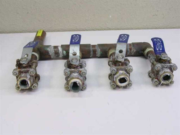 4-valve copper chilled water manifold bottom view showing open 1/2-inch branch ports and Nibco brass ball valve bodies with wear patina