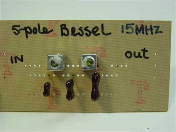5-pole Bessel 15 MHz low pass filter card — close-up top view showing SMA connectors, ceramic capacitors, and hand-inked IN/OUT markings