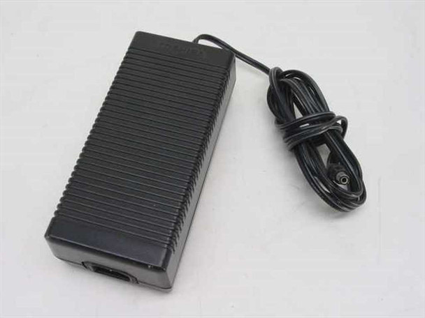 Toshiba PA7487U AC adapter — three-quarter top view showing ribbed black housing and attached barrel plug output cable coiled alongside