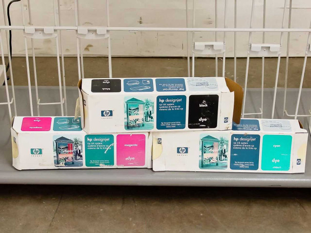 HP DesignJet ink cartridge boxes — black, magenta, and cyan dye cartridges on lower shelf of stand