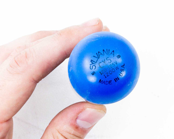 Close-up of blue protective cap on Sylvania CYS-DBH lamp showing printed markings: Sylvania, CYS, 120-125V, 1200W, Made in USA