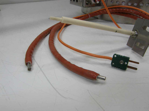 Close-up of thermocouple leads — ceramic probe, orange high-temperature silicone-jacketed wire, and green Type-K miniature thermocouple connector plug