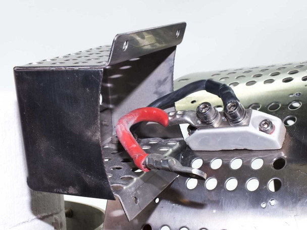 Close-up of furnace terminal block area — black sheet metal terminal enclosure, two stud terminals with red wire lead, mounted on perforated stainless furnace shell bracket
