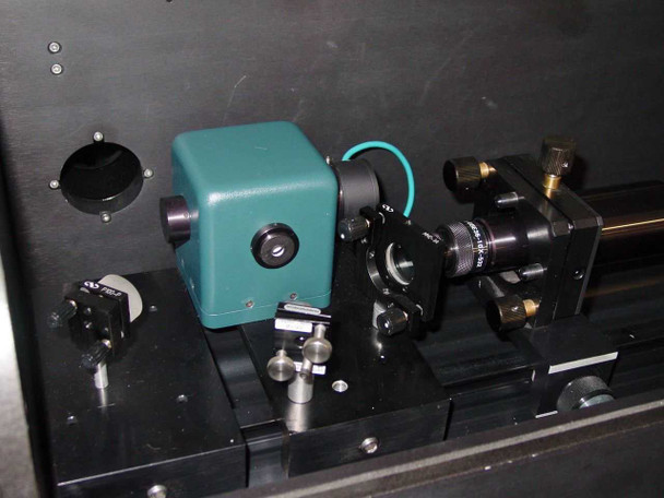 CMS PS-700 internal optics bench — Coherent Compass laser head (teal housing), beam steering optics, mirror mounts, and rail assembly visible