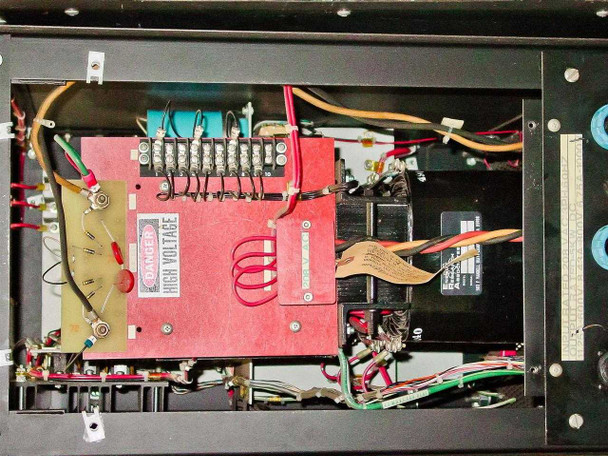 Internal chassis view – upper section showing red high-voltage transformer assembly with terminal block, warning label, and associated wiring
