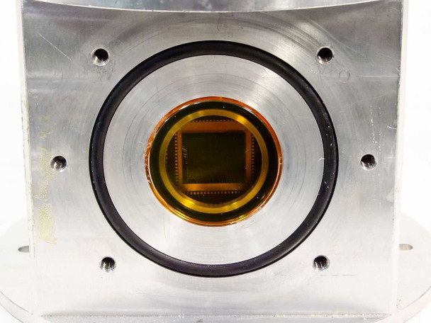 Close-up of CCD imaging detector face through circular vacuum chamber aperture — rectangular sensor chip array visible with orange/gold anti-reflection coating and black O-ring vacuum seal