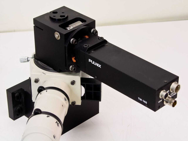 Pulnix TM-745 camera head close-up on black anodized bracket assembly mounted over white microscope body tube, showing PULNIX and TM-745 labeling
