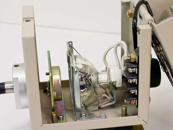 Interior of fiber optic light source unit with cover removed, showing lamp and reflector assembly, wiring, lamp socket, and internal mounting hardware